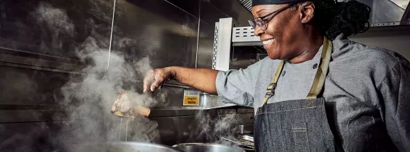 Elior's team chef cooking over a pot in the kitchen